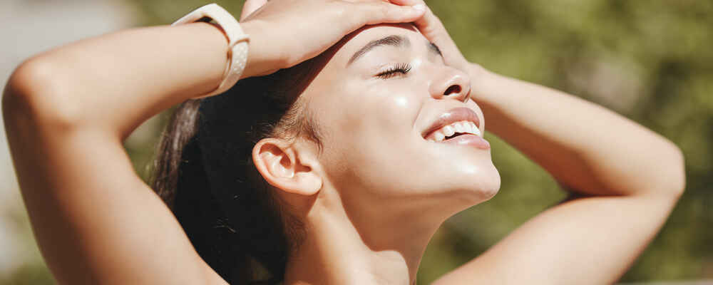 Woman outside with her hands on her forehead and looking relieved and happy