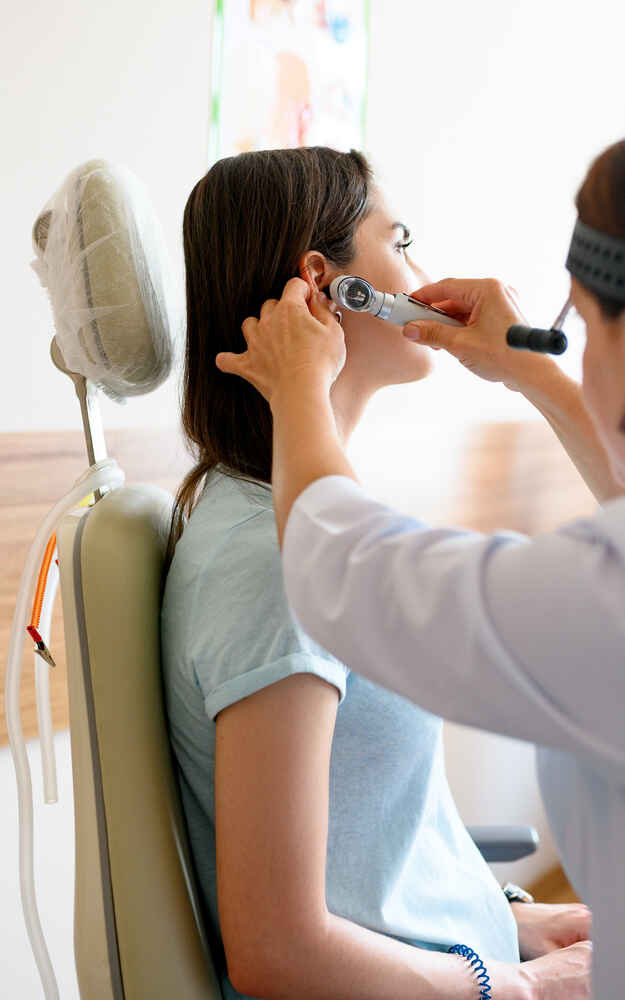 ENT doctor examining pediatric patient's ear to check for any issues
