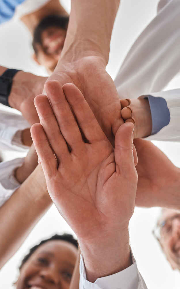 Doctors stackings hands together to represent teamwork