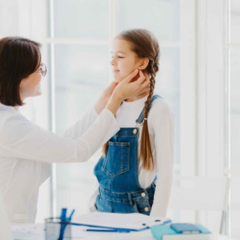 Female pediatrician examines child's throat
