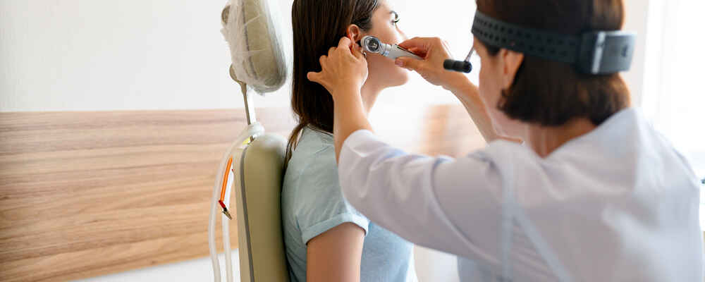 ENT doctor examining pediatric patient's ear to check for any issues
