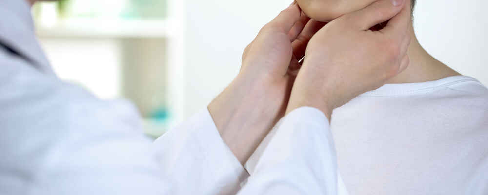Doctor pressing fingers against patient's neck to check for issues