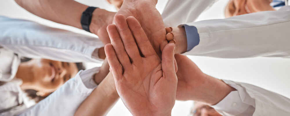 Doctors stackings hands together to represent teamwork