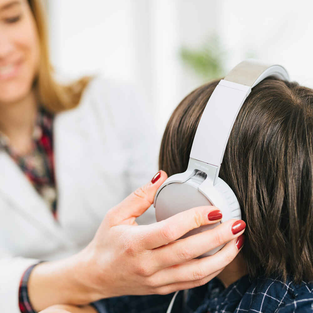 Doctor putting headphone on patient for hearing test